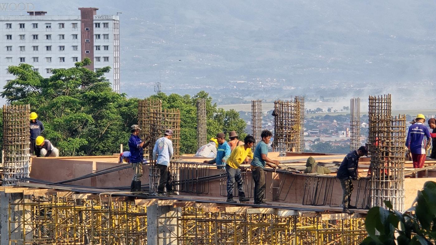 Workers building a structural frame on a construction site.