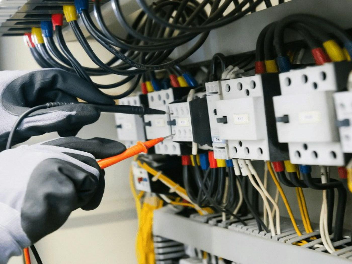 Electrician testing an electrical panel with a multimeter.