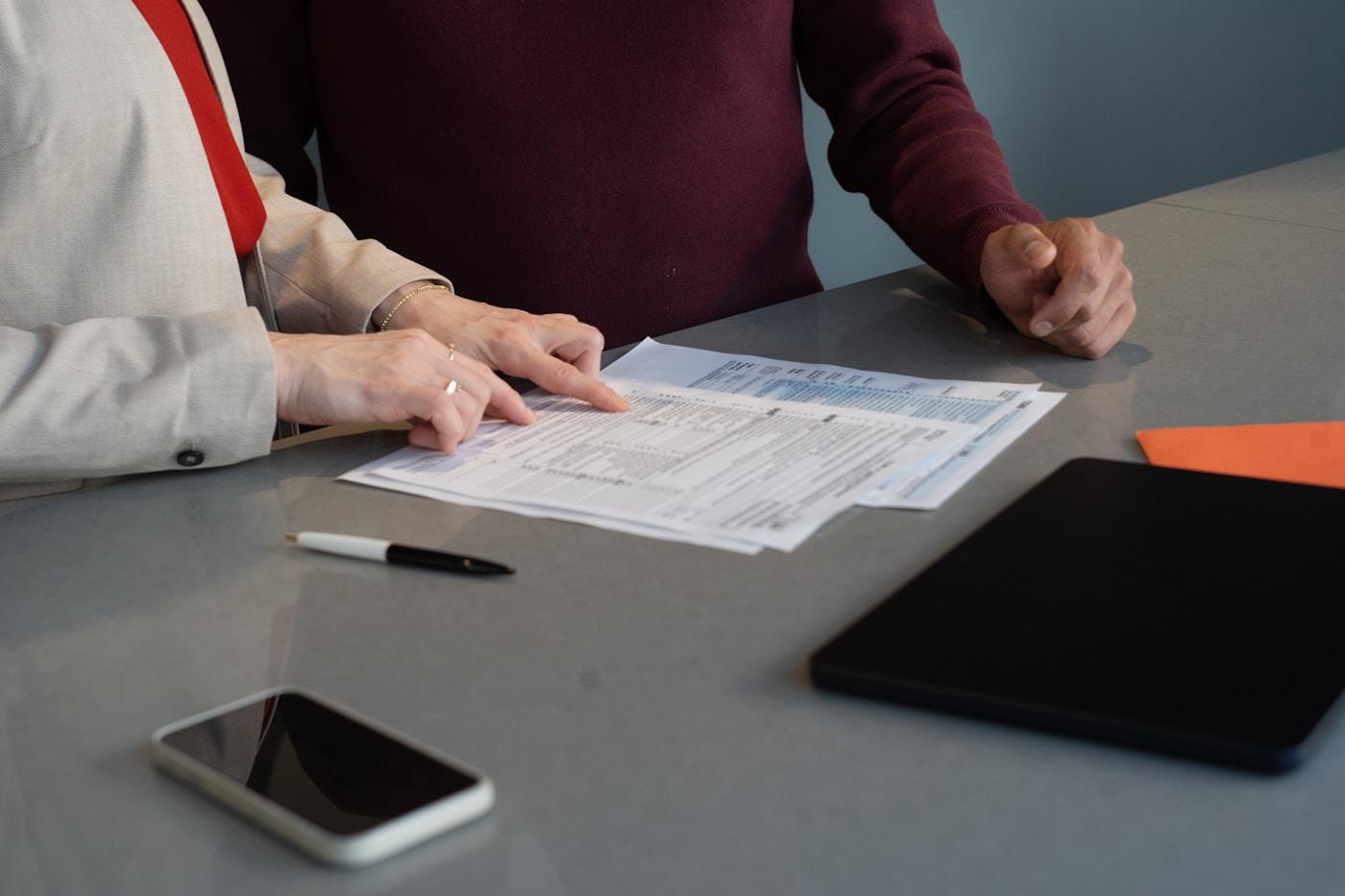 Two professionals reviewing documents together at a meeting table.